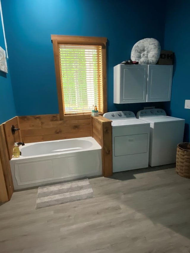 laundry room featuring cabinets, washing machine and dryer, and light hardwood / wood-style flooring