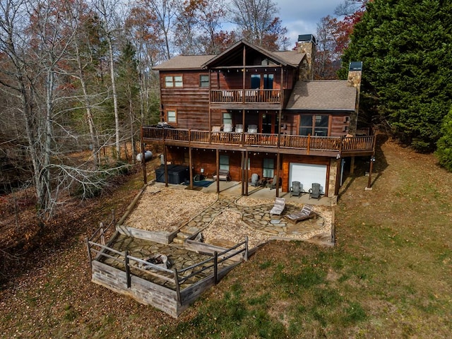 back of house with a balcony, a wooden deck, a patio area, a yard, and a garage