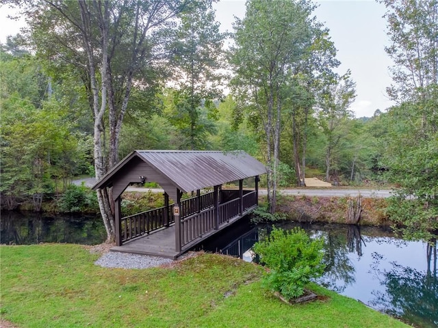 dock area with a gazebo, a water view, and a lawn