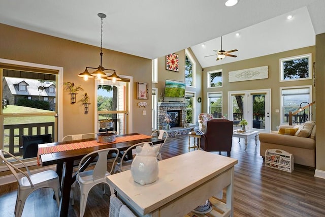 dining space featuring dark hardwood / wood-style floors, a healthy amount of sunlight, ceiling fan, and a stone fireplace