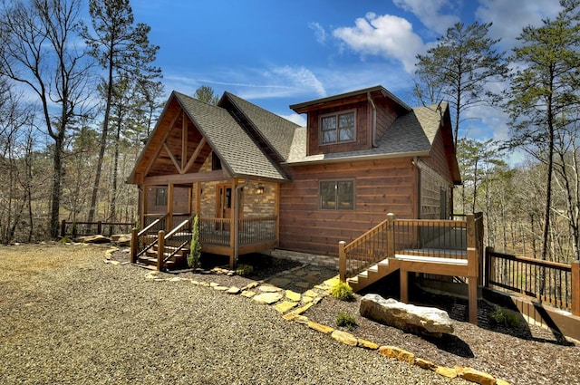 rear view of house featuring a shingled roof and a wooden deck