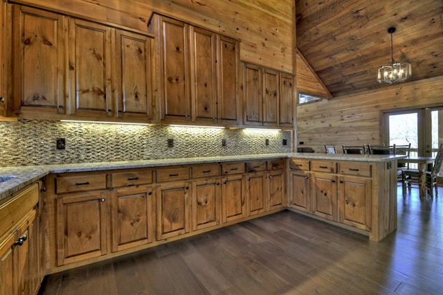 kitchen with a peninsula, tasteful backsplash, lofted ceiling, dark wood-style floors, and brown cabinetry