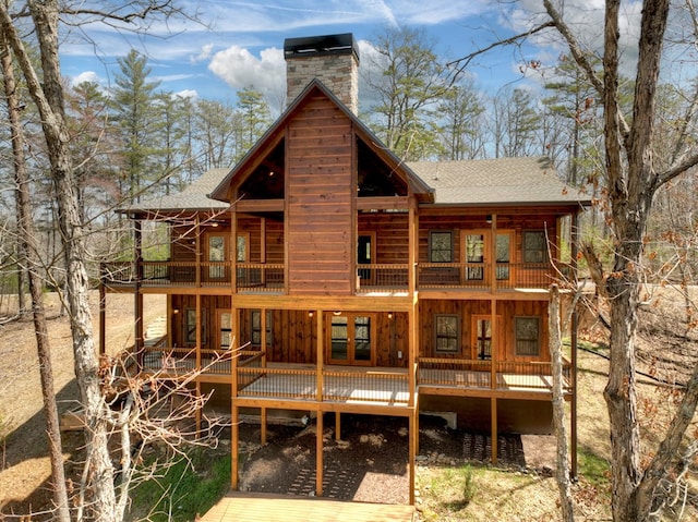 rear view of property featuring a chimney and roof with shingles