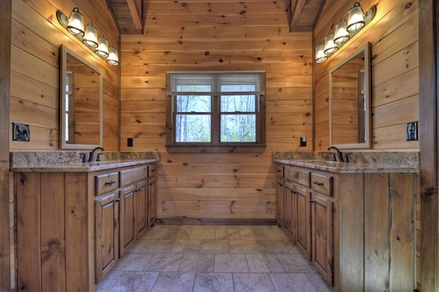 bathroom with a sink, wood walls, and two vanities