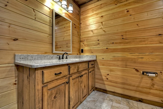 bathroom with wood walls, stone finish floor, and vanity