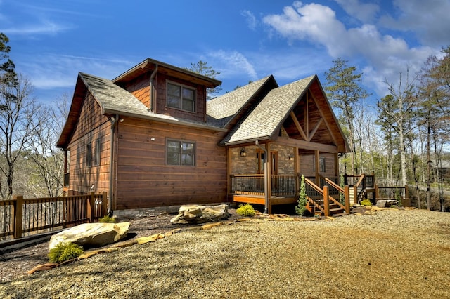 exterior space featuring roof with shingles and a deck