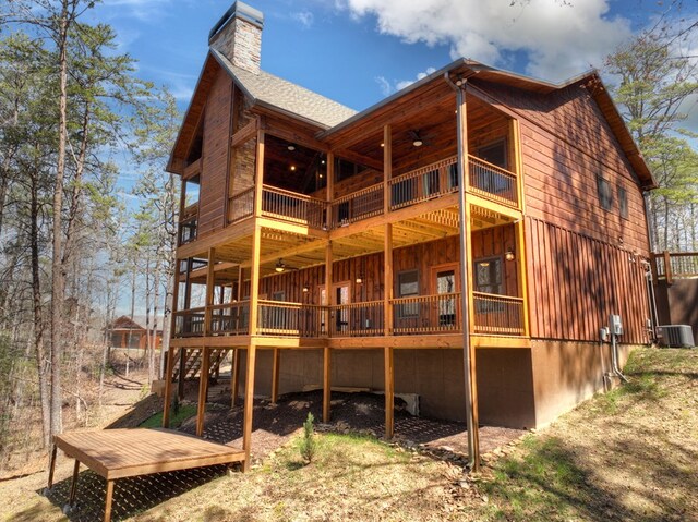 back of property featuring a chimney, central air condition unit, a wooden deck, and board and batten siding