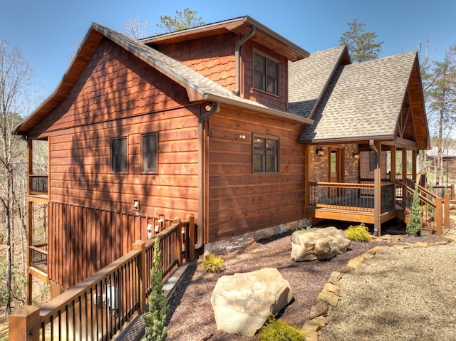 view of side of property with a deck and roof with shingles