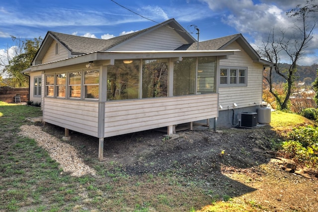 rear view of house featuring central AC unit and a sunroom