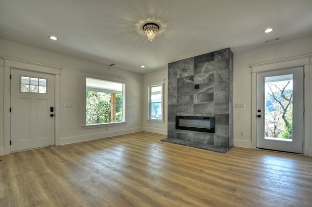 unfurnished living room with a tile fireplace, light hardwood / wood-style floors, and an inviting chandelier