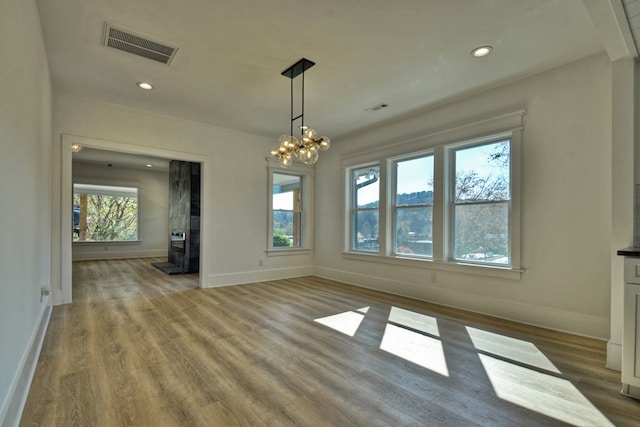 unfurnished dining area with a notable chandelier and wood-type flooring