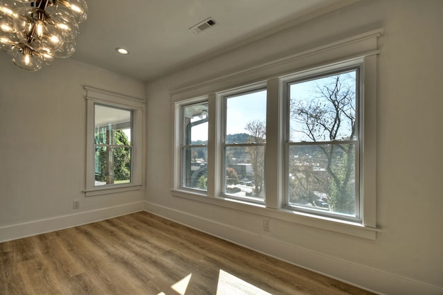 spare room with wood-type flooring and a chandelier