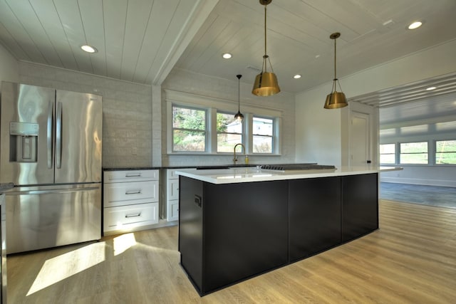 kitchen with white cabinets, a center island, light wood-type flooring, and appliances with stainless steel finishes