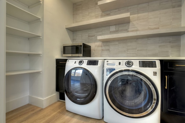 washroom featuring cabinets, light wood-type flooring, and separate washer and dryer