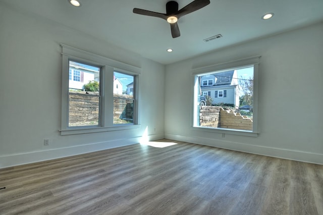 empty room with hardwood / wood-style flooring, ceiling fan, and a healthy amount of sunlight