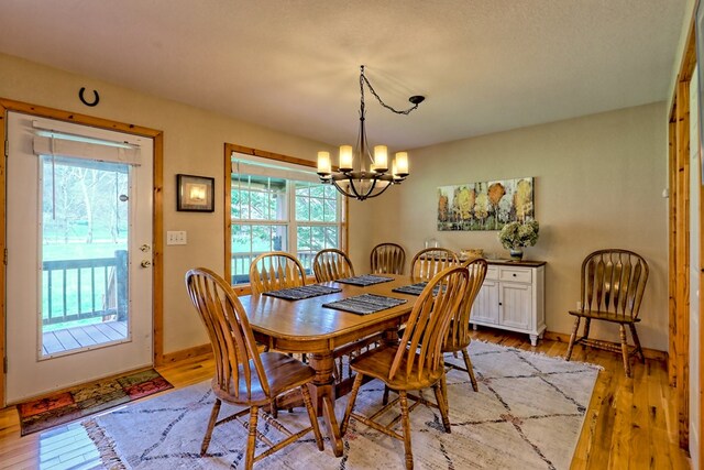 dining room with a wealth of natural light, light wood finished floors, and a notable chandelier