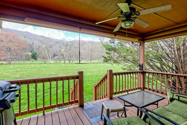 wooden terrace with a yard, outdoor dining area, a grill, and ceiling fan