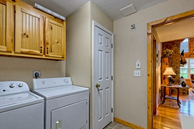 clothes washing area with cabinet space, baseboards, washer and dryer, and a textured ceiling