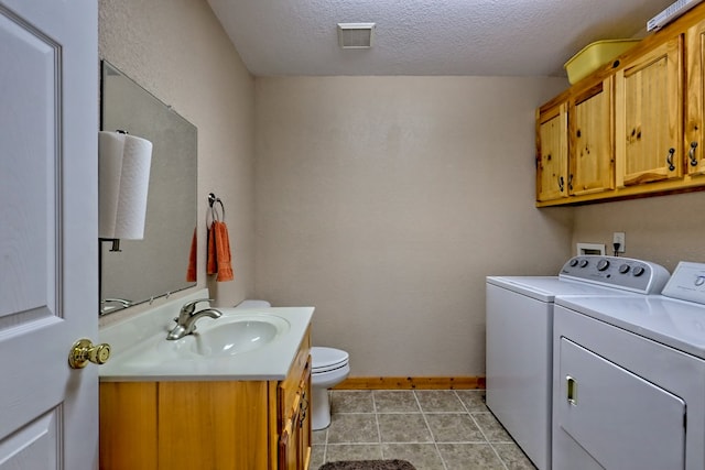 clothes washing area featuring baseboards, visible vents, washer and clothes dryer, laundry area, and a sink