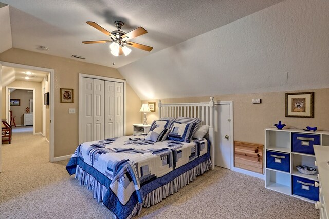 bedroom with a closet, a textured ceiling, light colored carpet, and lofted ceiling