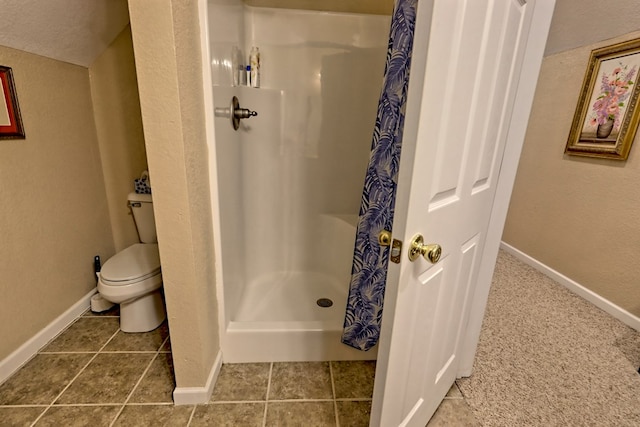 full bathroom featuring toilet, baseboards, a stall shower, and a textured wall