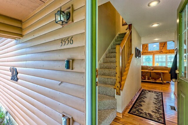 stairway featuring hardwood / wood-style floors, log walls, and recessed lighting