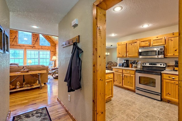 kitchen featuring a textured ceiling, a textured wall, light countertops, and stainless steel appliances