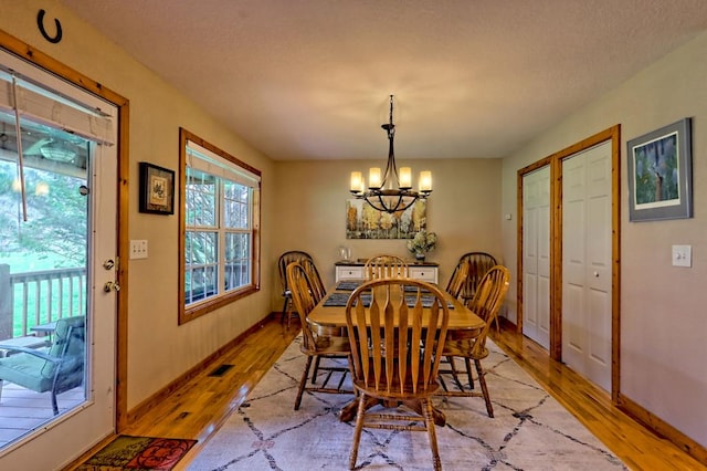 dining room featuring visible vents, baseboards, light wood-type flooring, and an inviting chandelier