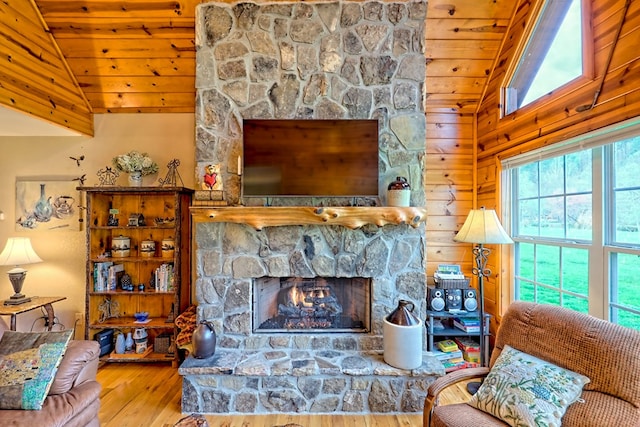 living area featuring hardwood / wood-style flooring, wood ceiling, wooden walls, a fireplace, and vaulted ceiling