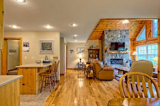 living room with a fireplace, light wood-style flooring, baseboards, and vaulted ceiling