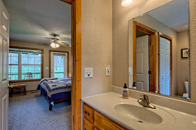 ensuite bathroom featuring a textured wall, ensuite bath, vanity, and ceiling fan