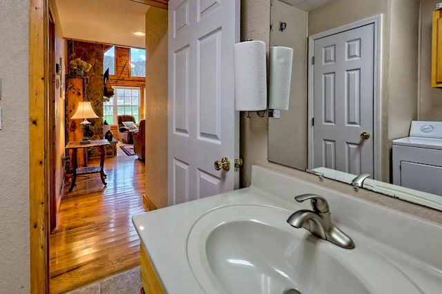 bathroom featuring a sink, washer / clothes dryer, and wood finished floors