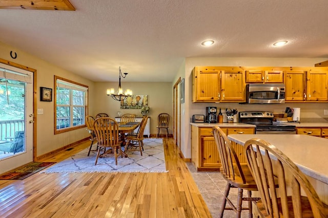 kitchen featuring light wood-style flooring, a textured ceiling, light countertops, and stainless steel appliances
