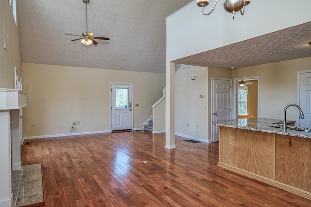 unfurnished living room featuring a sink, a textured ceiling, and a ceiling fan