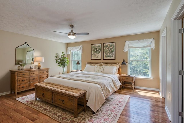 bedroom featuring baseboards, hardwood / wood-style floors, and a textured ceiling