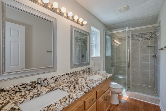 bathroom featuring a sink, toilet, a shower stall, and a textured ceiling