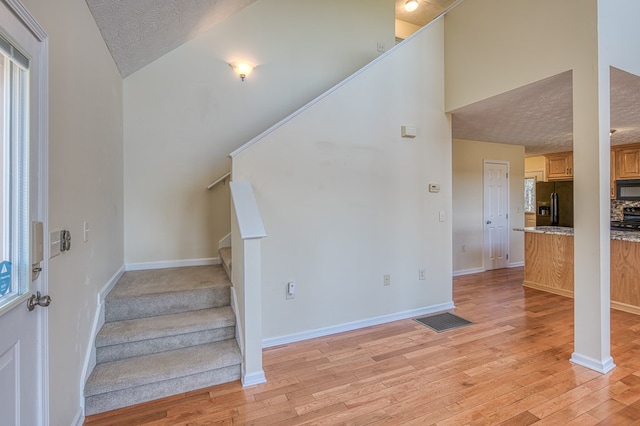stairway with visible vents, a textured ceiling, baseboards, and wood finished floors
