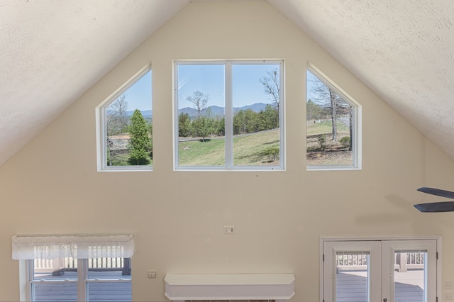 additional living space with a textured ceiling, high vaulted ceiling, a mountain view, and ceiling fan