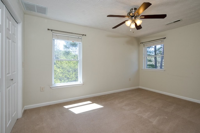 spare room with carpet flooring, a ceiling fan, and visible vents