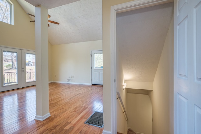 interior space featuring ceiling fan, a textured ceiling, visible vents, lofted ceiling, and light wood finished floors