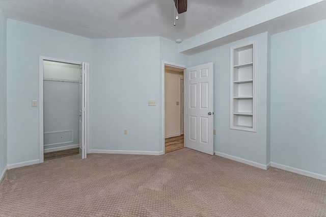 unfurnished bedroom with ceiling fan, a closet, light colored carpet, and baseboards