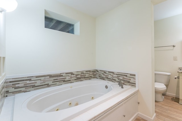 full bath with toilet, a jetted tub, wood finished floors, and baseboards