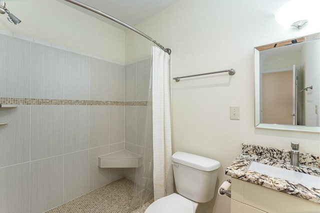 full bath with a tile shower, vanity, and toilet