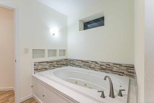 bathroom with wood finished floors, baseboards, and a whirlpool tub