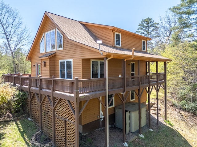 rear view of property featuring roof with shingles and a deck