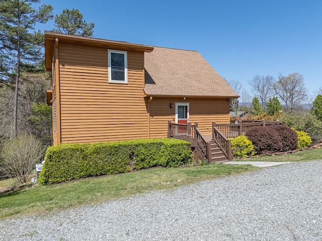rustic home featuring roof with shingles and a wooden deck