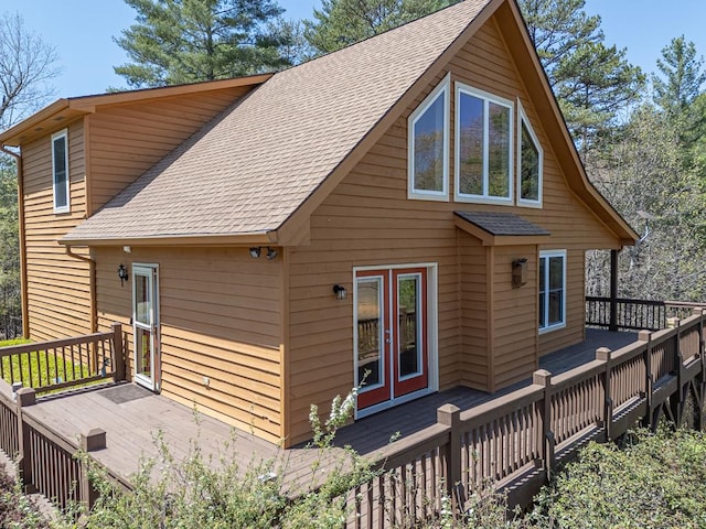 back of house featuring roof with shingles and a wooden deck