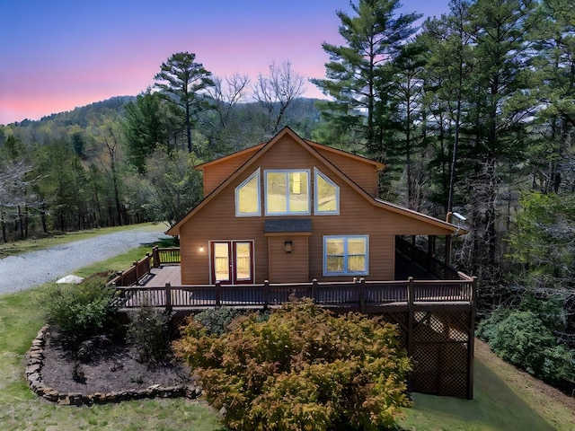 back of house featuring a view of trees and a wooden deck
