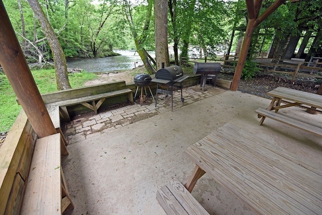 wooden deck featuring a water view, a grill, and a patio