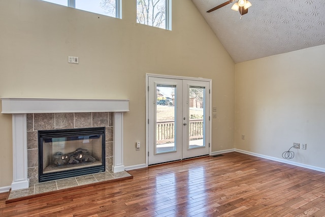 unfurnished living room featuring high vaulted ceiling, a wealth of natural light, hardwood / wood-style flooring, and ceiling fan